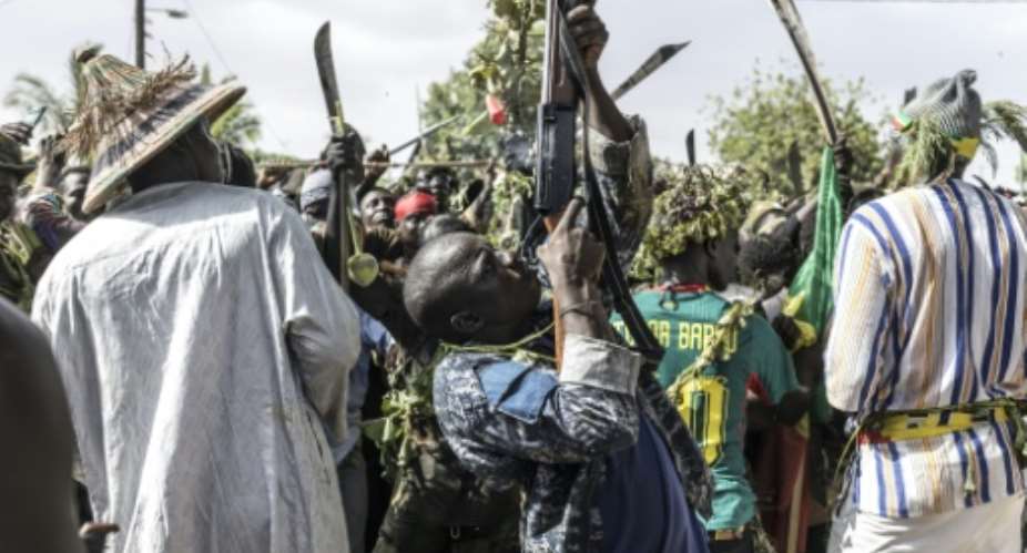 A man shoots down a bird as he arrives with other hunters to display their catch to community members at an arena, during the Miss de Diobaye on July 13, 2026.  By PATRICK MEINHARDT (AFP)
