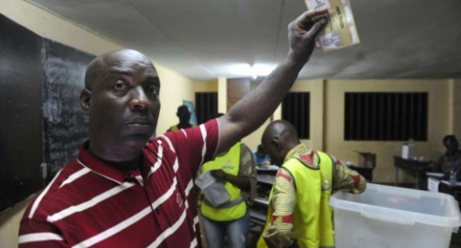 A man shows a ballot paper during counting in a polling station at the Montagne sainte neighborhood in Libreville on August 27, 2016.  By Steve Jordan AFP