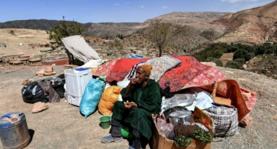 A man sits by salvaged items in the Moroccan village of Ighermane near Adassil, after the earthquake left survivors facing 'terrible conditions,' an aid volunteer said.  By FETHI BELAID AFP