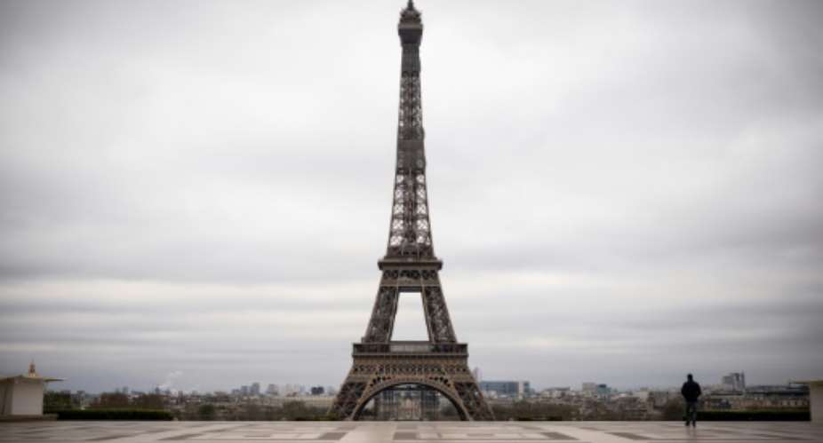 A man walks on the deserted square in front of the Eiffel Tower on March 21, 2020 -- worldwide, almost one billion people have been asked to stay at home to curb the spread of the novel coronavirus.  By Lionel BONAVENTURE AFP