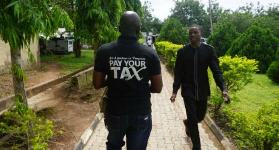 A man wearing a t-shirt that says Pay Your Tax in Nigeria, where tax is no longer a laughing matter.  By PIUS UTOMI EKPEI AFP