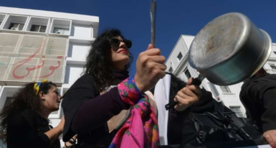 A member of the Tunisian EnaZeda, Me too movement bangs a pot at a rally against sexual harassment in Tunis on November 30, 2019.  By FETHI BELAID AFP
