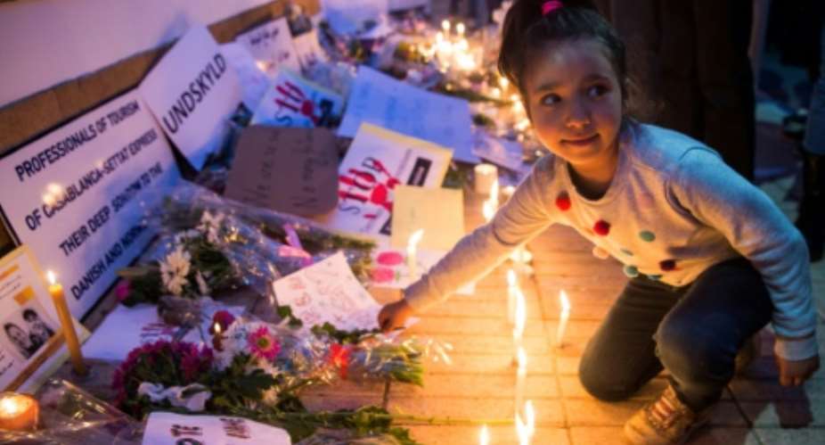 A Moroccan girl places a flower during a vigil for the two Scandinavian hikers, who were killed in Morocco's High Atlas mountains, outside the Danish Embassy in Rabat on December 22, 2018.  By FADEL SENNA AFP