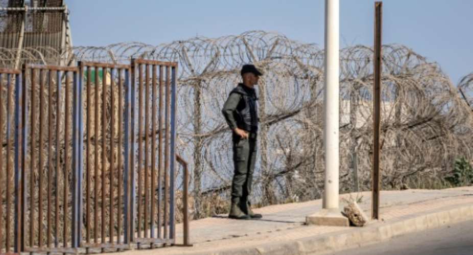 A Moroccan security officer stands guard on the border fence with Spain's North African Melilla enclave.  By FADEL SENNA AFP