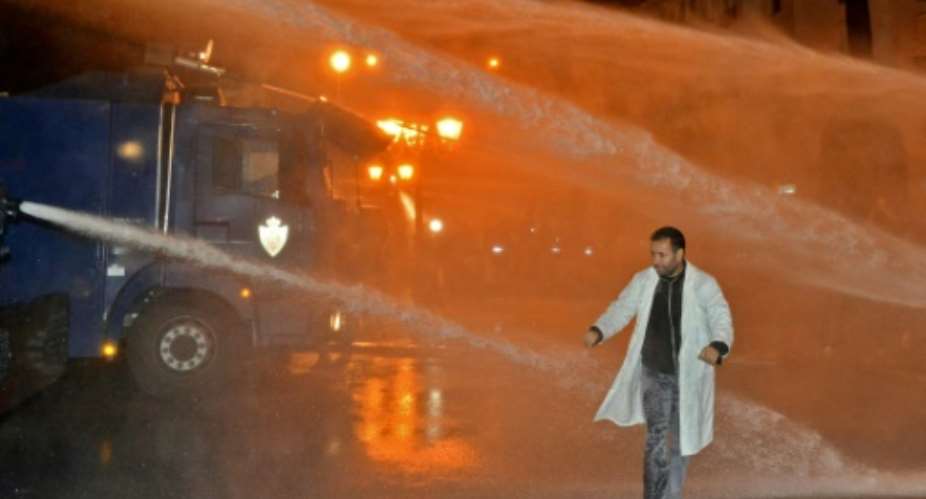 A Moroccan teacher walks through a water cannon during a demonstration calling for permanent contracts.  By - AFP