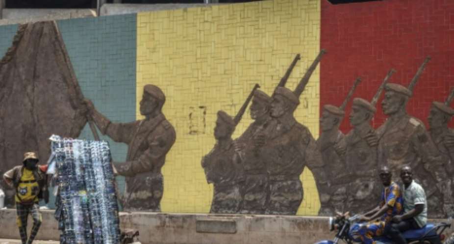A motorcyclist rides past a monument in support of the Malian army in Bamako on April 26, the day after the attacks began.  By - (AFP)
