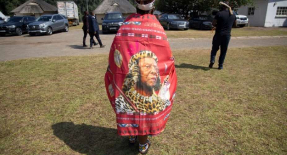 A mourner at last week's funeral wears a cloak bearing the image of the king.  By Phill Magakoe POOLAFP