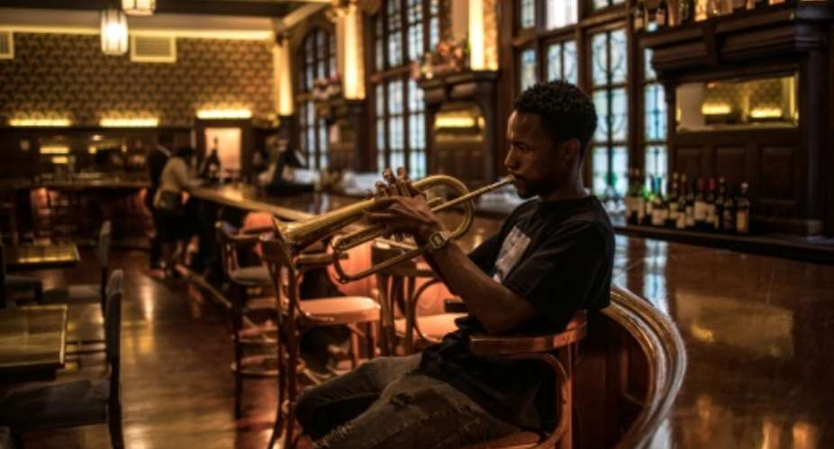 A musician plays at the bar of the Rand Club, the imposing Edwardian-style club in Johannesburg's vibrant centre.  By MARCO LONGARI AFP