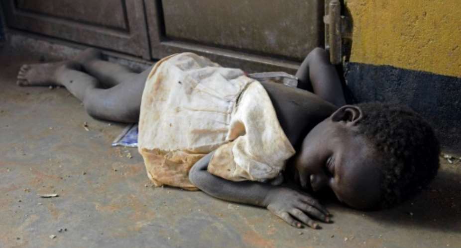 A newly arrived refugee child from South Sudan sleeps on a dirty floor on the Ugandan side of the Ngomoromo border post.  By ISAAC KASAMANI AFPFile