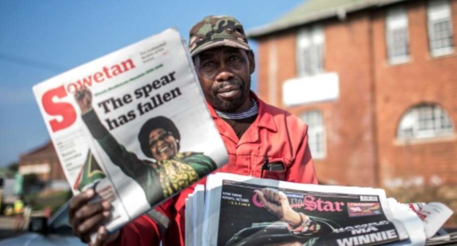 A newspaper vendor holds up a copy featuring a story on of death of South African anti-apartheid campaigner Winnie Madikizela-Mandela, in Johannesburg on April 3, 2018.  By Gulshan KHAN AFP