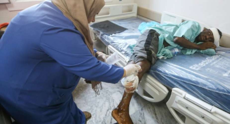 A nurse cleans the wound of a wounded migrant at a medical emergency ward in a Tripoli hospital on Wednesday.  By Mahmud TURKIA AFP