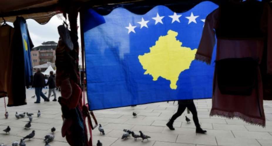 A pedestrian walks behind the Kosovo flag ahead of last year's 10th-anniversary celebrations in Pristina of Kosovo's declaration of independence.  By Armend NIMANI AFP