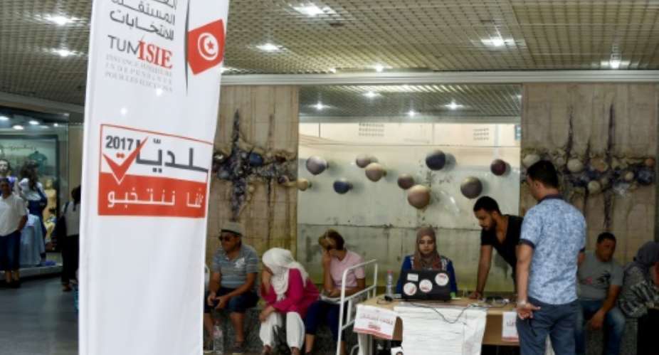 A picture taken on August 4, 2017 shows employees of the Tunisian ISIE elections body sitting at an outreach booth at a shopping mall in the capital Tunis, in a bid to encourage citizens to register to vote in the upcoming municipal elections.  By FETHI BELAID AFPFile