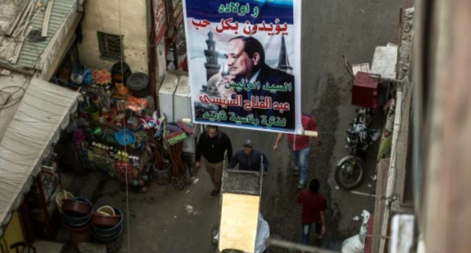 A picture taken on March 7, 2018 shows posters supporting Egyptian President Abdel Fattah al-Sisi hanging in a street in the downtown Cairo district of El-Gamaleya, where he was born.  By KHALED DESOUKI AFP