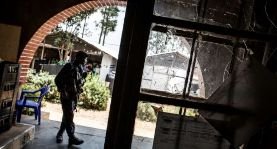 A police officer stands guard beside a window full of bullet holes at an Ebola treatment centre in Butembo.Suspected Mai-Mai tribal militia raided the ETC and killed a policeman and wounded a health worker early in March.  By JOHN WESSELS AFPFile