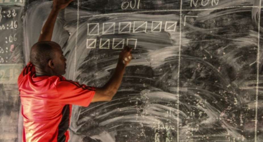 A polling station official marks the results on a blackboard at a school.  By Ibrahim YOUSSOUF AFP