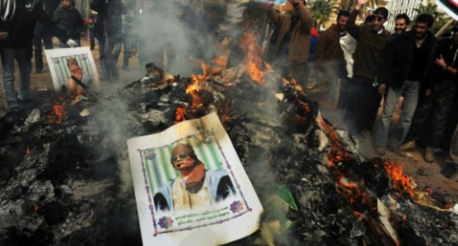 A portrait of Libyan strongman Moamer Kadhafi burns ontop of a pile of ashes accumulated after hundreds of copies of his green book were burned in Benghazi on March 02, 2011.  By Roberto Schmidt AFPFile