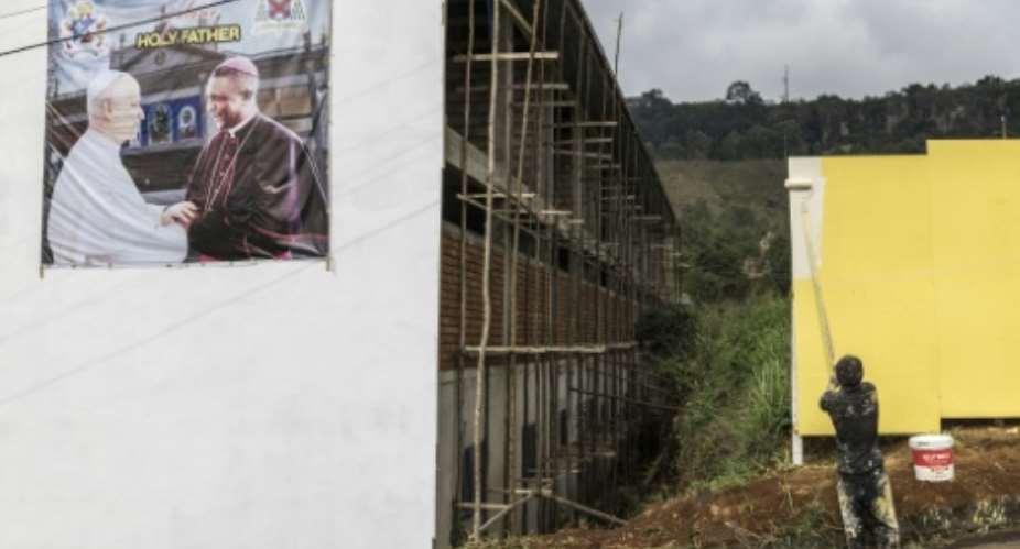 A poster portraying Pope Leo XIV (L) and Archbishop of Bamenda Andrew Nkea (R) at the Saint Joseph Metropolitan Cathedral.  By PATRICK MEINHARDT (AFP)