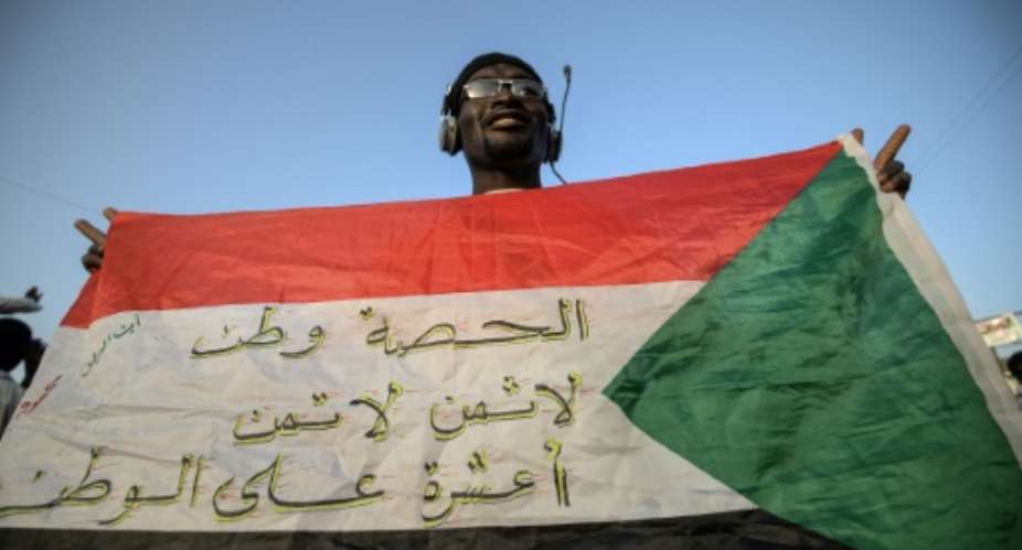 A protester flashes a Sudanese flag covered with patriotic slogans outside army headquarters in Khartoum.  By Mohamed el-Shahed AFP