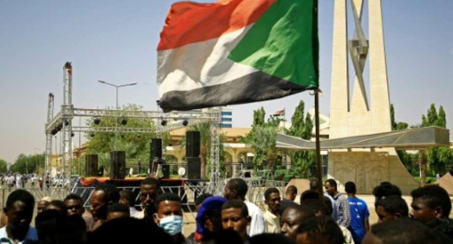 A protester holds a national flag during a sit-in demanding the dissolution of Sudan's post-dictatorship interim government, outside the presidential palace in Sudan's capital on Monday.  By ASHRAF SHAZLY AFP