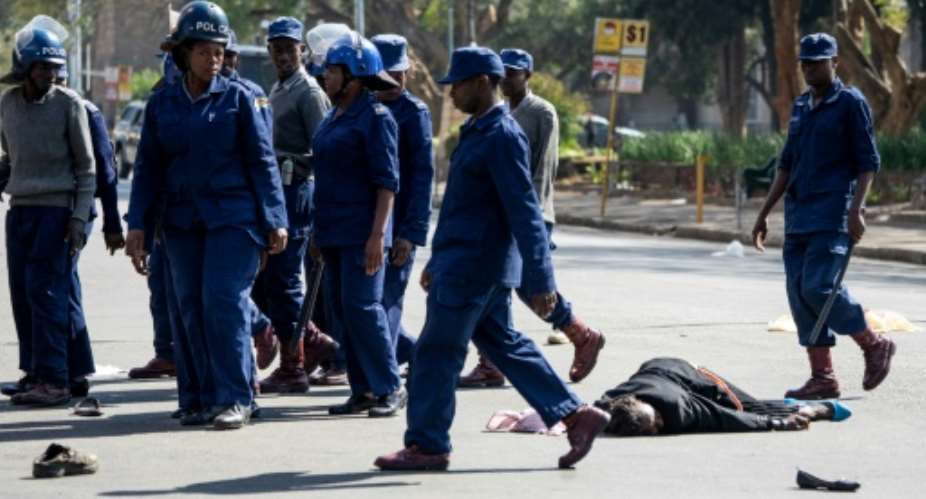 A protester lies on the ground after being beaten by police.  By Zinyange Auntony AFP