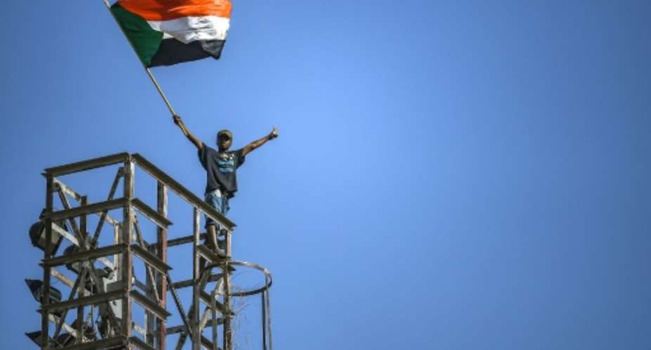 A protester waves a Sudanese flag on top of a tower during a sit-in outside the army headquarters in the capital Khartoum on April 30, 2019.  By OZAN KOSE AFP