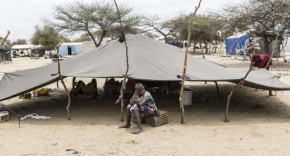 A refugee sits outside a tent at a makeshift camp in Doueinkara, near the Mauritanian border with Mali on April 28, 2026.  By PATRICK MEINHARDT (AFP)