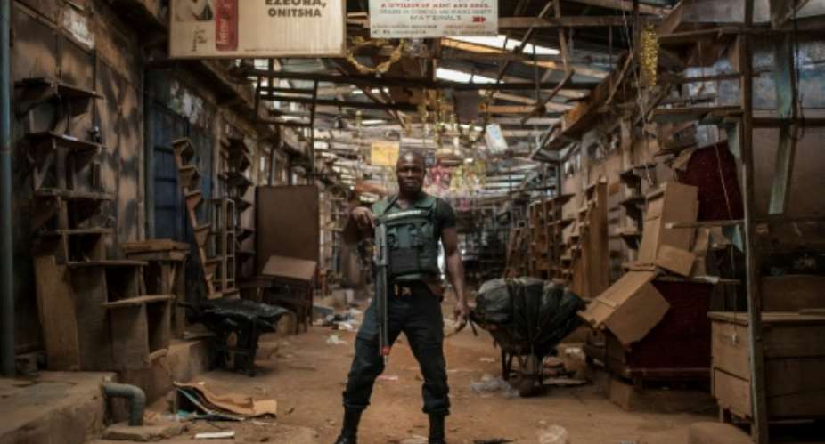 A security guard poses in an empty alleyway in Ogbaru Market in May 2017, during a shutdown in commemoration of the 50th anniversary of the Nigerian Civil War.  By STEFAN HEUNIS AFPFile