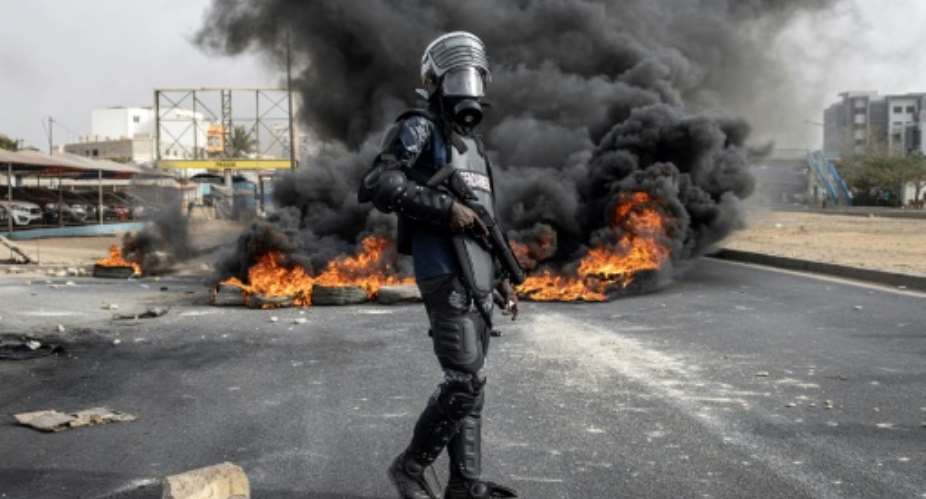 A Senegalese gendarme stands near smoke billowing from burning tyres during a protest in Dakar over the arrest of opposition leader Ousmane Sonko.  By JOHN WESSELS AFP