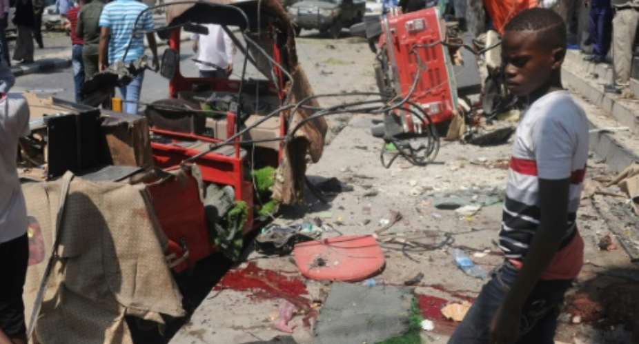 A Somali boy walks near blood-stains and debris on the ground after an explosion outside a restaurant in Mogadishu that left at least 15 people dead.  By MOHAMED ABDIWAHAB AFP