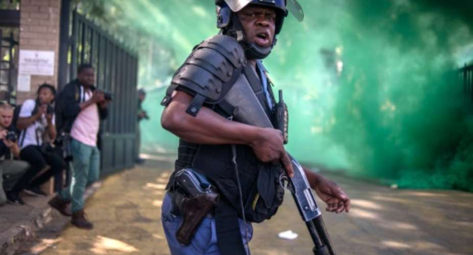 A South African police officer looks on during clashes with students from the University of the Witwatersrand during a protest against university fee increases in Johannesburg, on September 21, 2016.  By Mujahid Safodien AFPFile