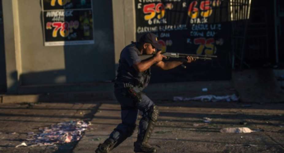 A South African riot police officer fires rubber bullets in North West Province in April 2018, as protests continue to occur, causing President Cyril Ramaphosa cut short a foreign trip to deal with riots over alleged government corruption.  By MUJAHID SAFODIEN AFPFile