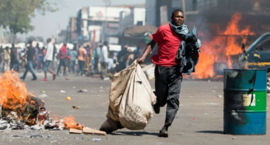 A street vendor flees with his goods as Zimbabwe opposition supporters clash with police in Harare on August 26, 2016.  By Wilfred Kajese AFPFile