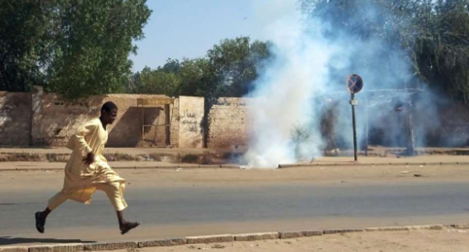 A Sudanese anti-coup protester eludes tear gas fired by security forces on a street in Khartoum.  By - (AFP)