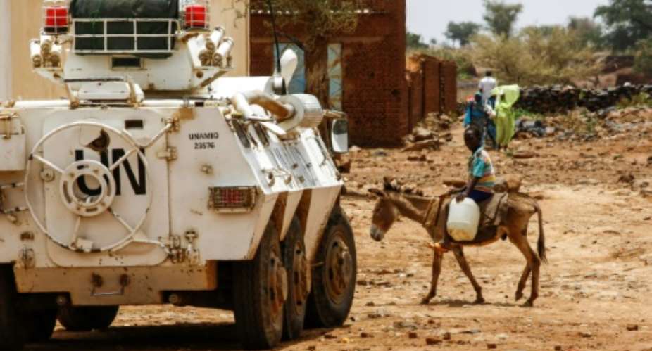A Sudanese boy rides a donkey past a UN-African Union mission in Darfur UNAMID armoured vehicle in the war-torn town of Golo in the thickly forested mountainous area of Jebel Marra in central Darfur on June 19, 2017.  By ASHRAF SHAZLY AFPFile