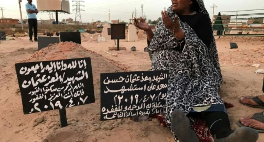 A Sudanese mother, Khadom, mourns at the grave of her son Al-Moez, who was killed when a bullet pierced the window of his workplace during anti-government demonstrations in April.  By Claire DOYEN AFP