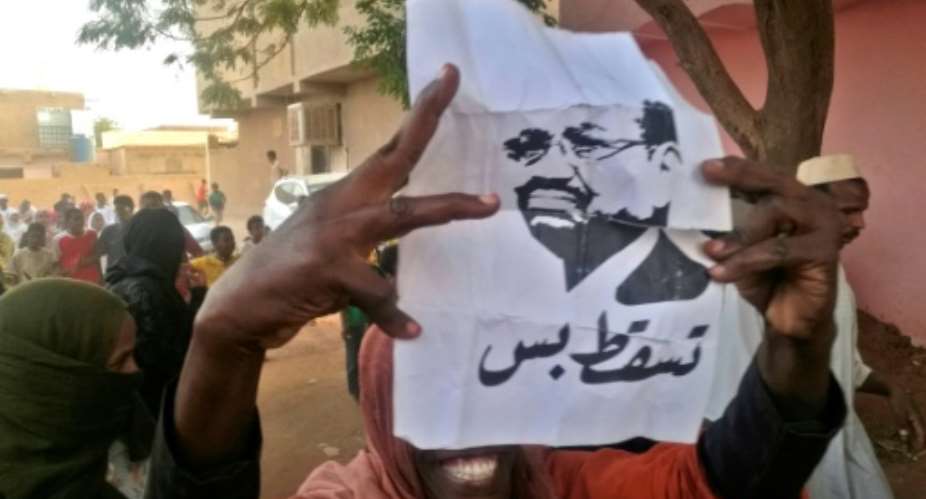 A Sudanese protester carries a portrait of President Omar al-Bashir with Arabic writing that reads