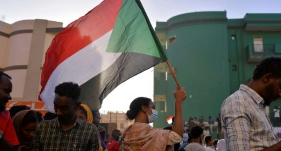 A Sudanese protester waves a flag during a rally in Khartoum following a deal-signing ceremony to restore the transition to civilian rule on November 21.  By - AFP