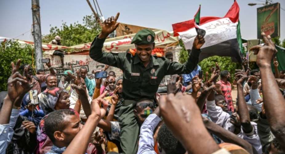 A Sudanese soldier joins protesters outside the army complex in Khartoum.  By OZAN KOSE AFP