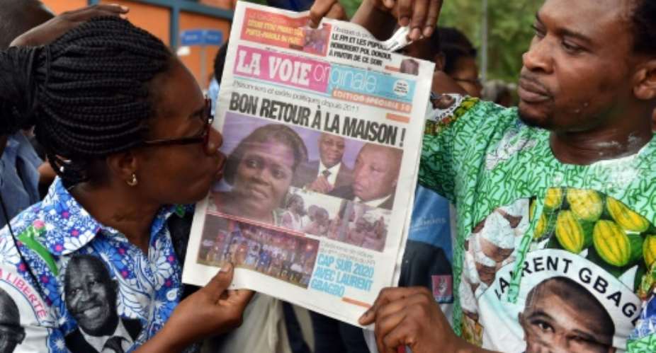 A supporter of Simone Gbagbo kisses a local newspaper bearing the headline Have a safe trip home!.  By ISSOUF SANOGO AFP