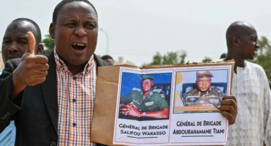 A supporter of the coup holds up a photo of new strongman General Abdourahamane Tiani at a rally in Niamey on Sunday.  By - AFP
