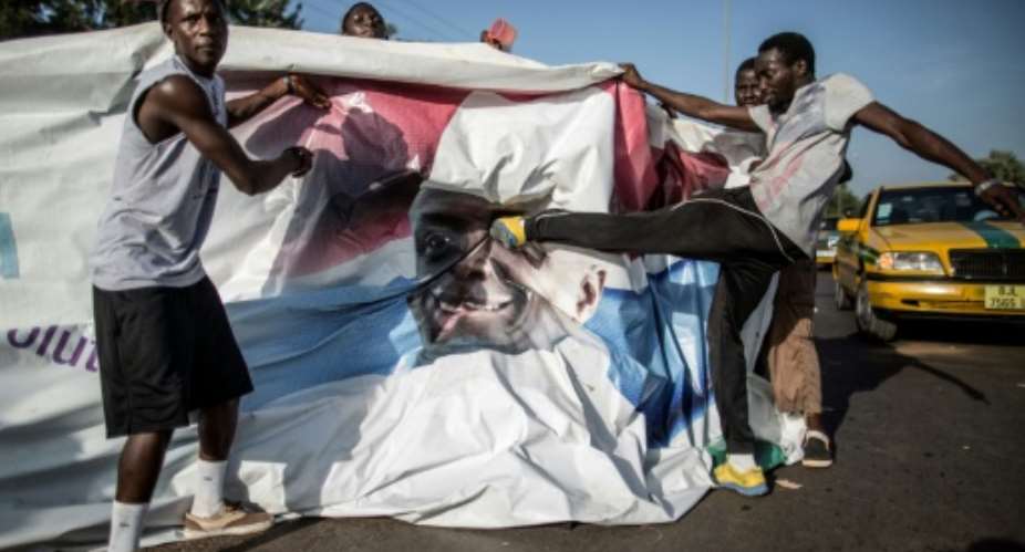 A supporter of the newly elected Gambia President Adama Barrow kicks a poster of the exiting leader Yahya Jammeh in Serekunda.  By MARCO LONGARI AFPFile
