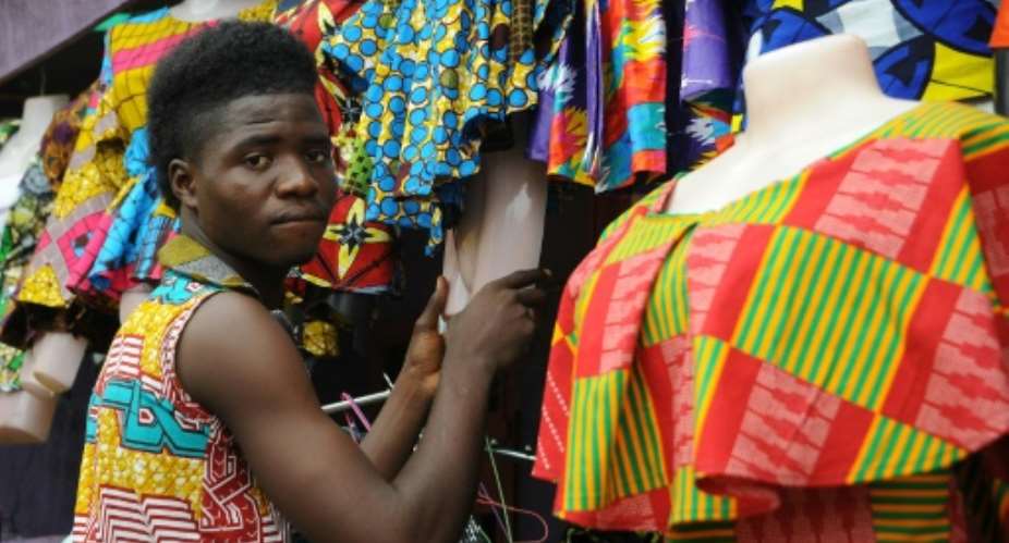 A tailor prepares clothes to sell at an African clothes shop in Monrovia.  By Zoom Dosso AFP