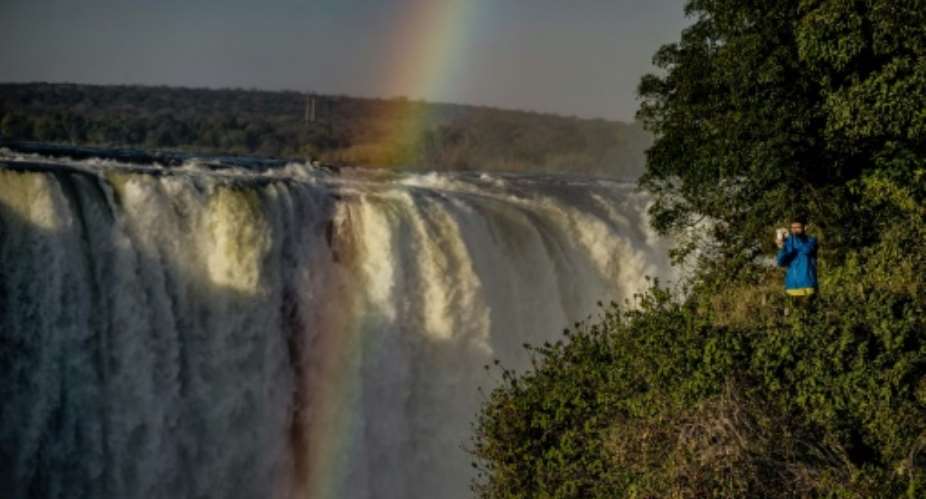 A tourist takes a photograph of the rainbow over Victoria Falls in Zimbabwe, where the number of tourists jumped by nearly 50 percent in the first quarter of tis year.  By Zinyange AUNTONY AFP