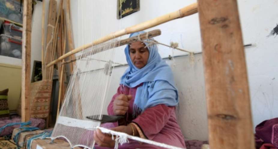 A Tunisian craftswoman weaves a rug at a workshop run by Shanti, a social enterprise that helps artisans from across the North African country.  By FETHI BELAID AFP