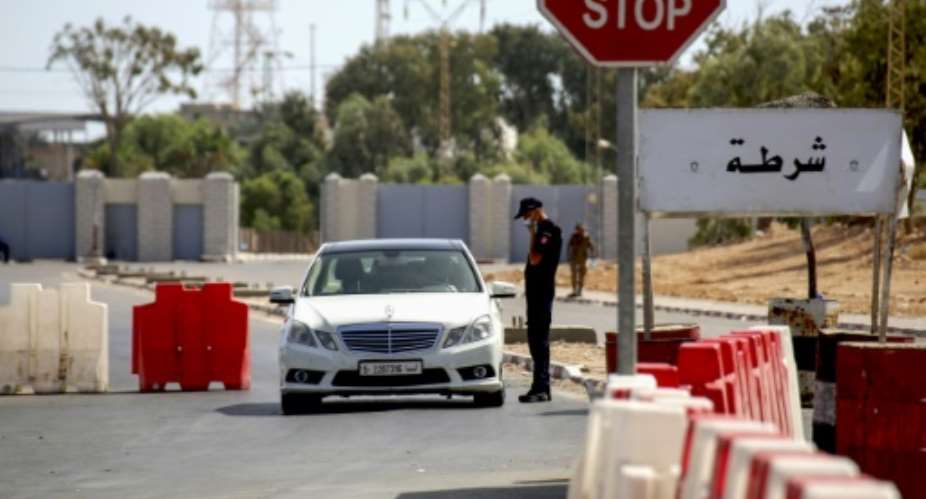 A Tunisian policeman checks a Libyan motorist at the Ras Jdeir border crossing between the two countries following its reopening after a two-month Covid closure.  By FATHI NASRI AFP