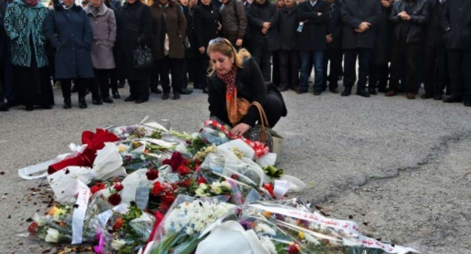 A Tunisian woman lays flowers at the site of the 2013 assassination of secular opposition leader Chokri Belaid on the fifth anniversary of his death.  By FETHI BELAID AFP