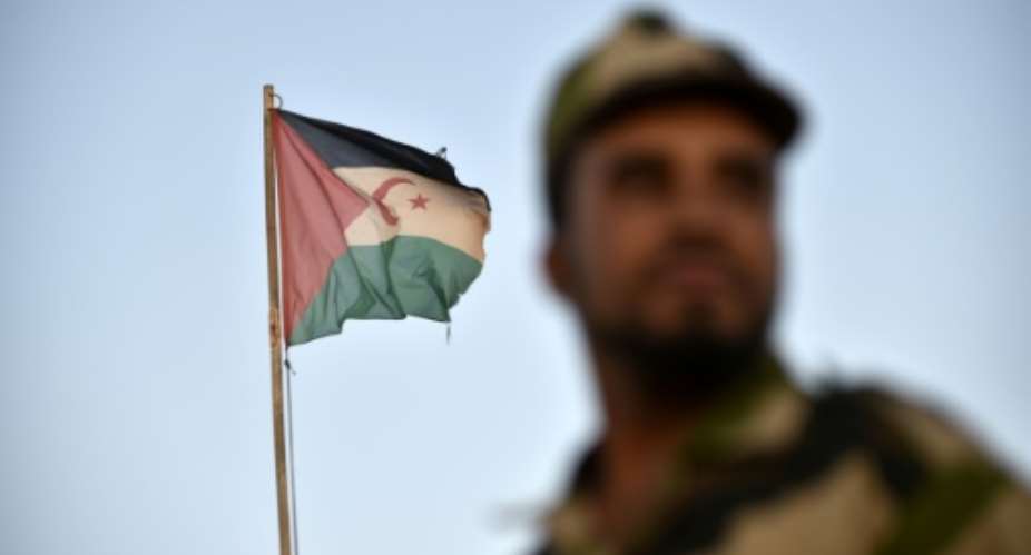 A uniformed soldier of the pro-independence Polisario Front stands before a Sahrawi flag flying at the Boujdour refugee camp near the town of Tindouf in Western Algeria on October 17, 2017..  By RYAD KRAMDI RYAD KRAMDIAFP