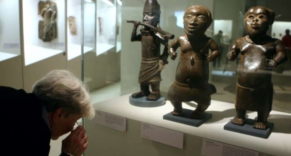A visitor looks at a statue in brass representing a horn player L, Benin, South of Nigeria, XVIth and XVIIth Century during an exhibition focused on refined Art in Benin in 2007 at the Quai Branly museum in Paris.  By OLIVIER LABAN-MATTEI AFPFile
