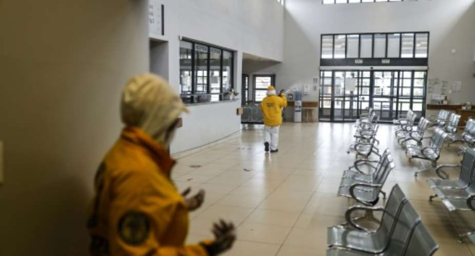 A volunteer sprays disinfectant during a deep cleaning operation inside the Villa Liza Clinic, in Ekurhuleni, South Africa, on January 14, 2021.  By Guillem Sartorio AFP